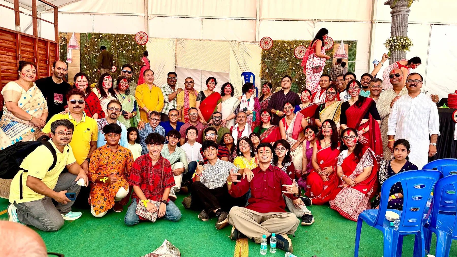Members of the Assamese community, faces red with sindoor, in a large group photograph on Vijaya Dashami 2025 before the visarjan of Devi Durga